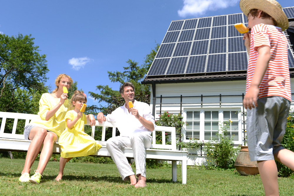 Family Sitting in Front of House with Solar Panels